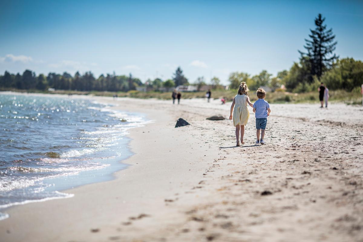 Kinder gehen bei Saksild über den Strand