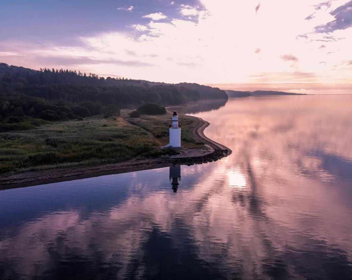 Ausblick auf Küste und Leuchtturm beim Hotel Vejlefjord im Küstenland