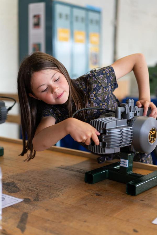 Mädchen spielt mit einem Motor im Industriemuseum in Horsens