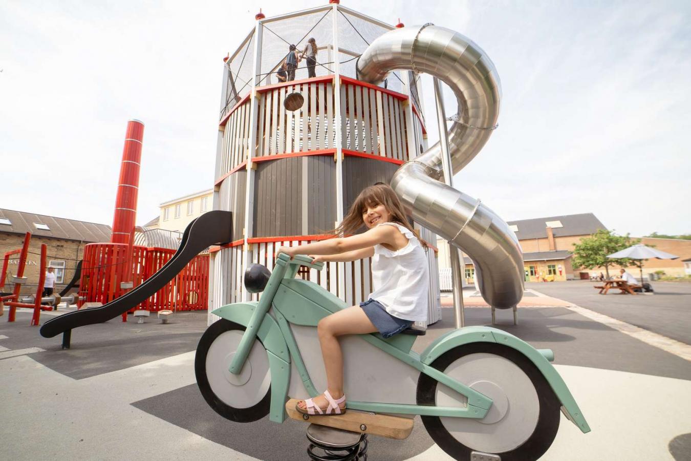 Mädchen sitzt auf Wipp-Motorrad auf dem Spielplatz des Industriemuseums