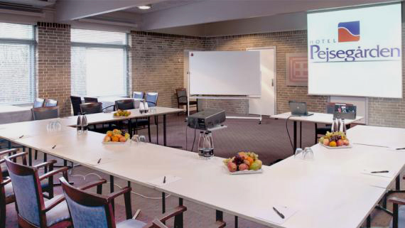 Mødelokale med bordopstilling og projektor på Hotel Pejsegården
