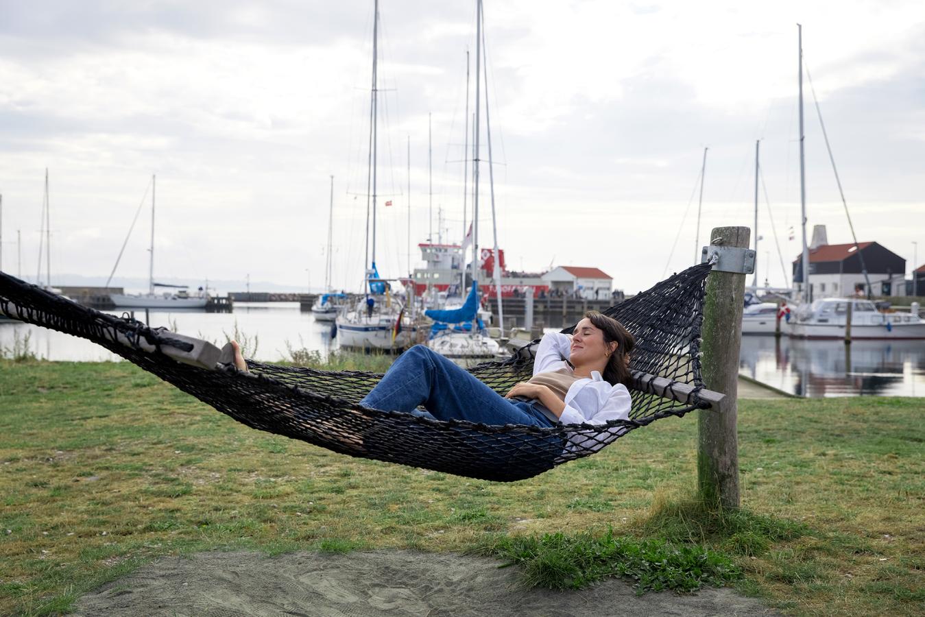 Kvinde slapper af i hængekøje på Tunø Havn - en del af Destination Kystlandet
