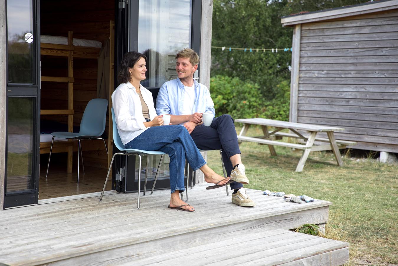 Paar sitzt und unterhält sich vor einer Hütte auf dem Zeltplatz von Tunø in der Urlaubsregion Küstenland