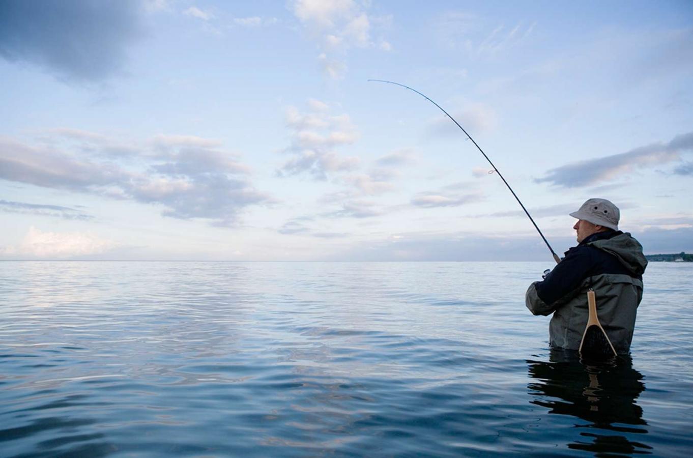 Man fishing in the sea at sunset