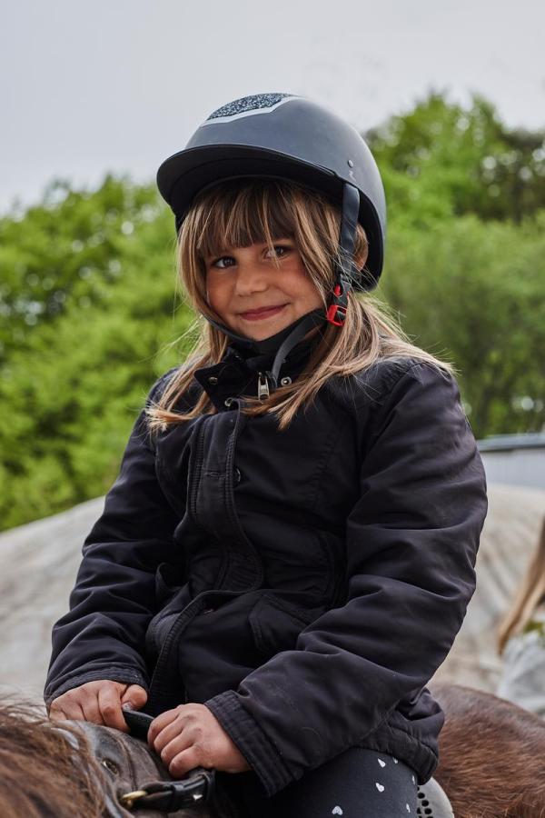 Ung pige sidder på hesteryg i Bakkelandet ved Fuglsang Rideture i Destination Kystlandet