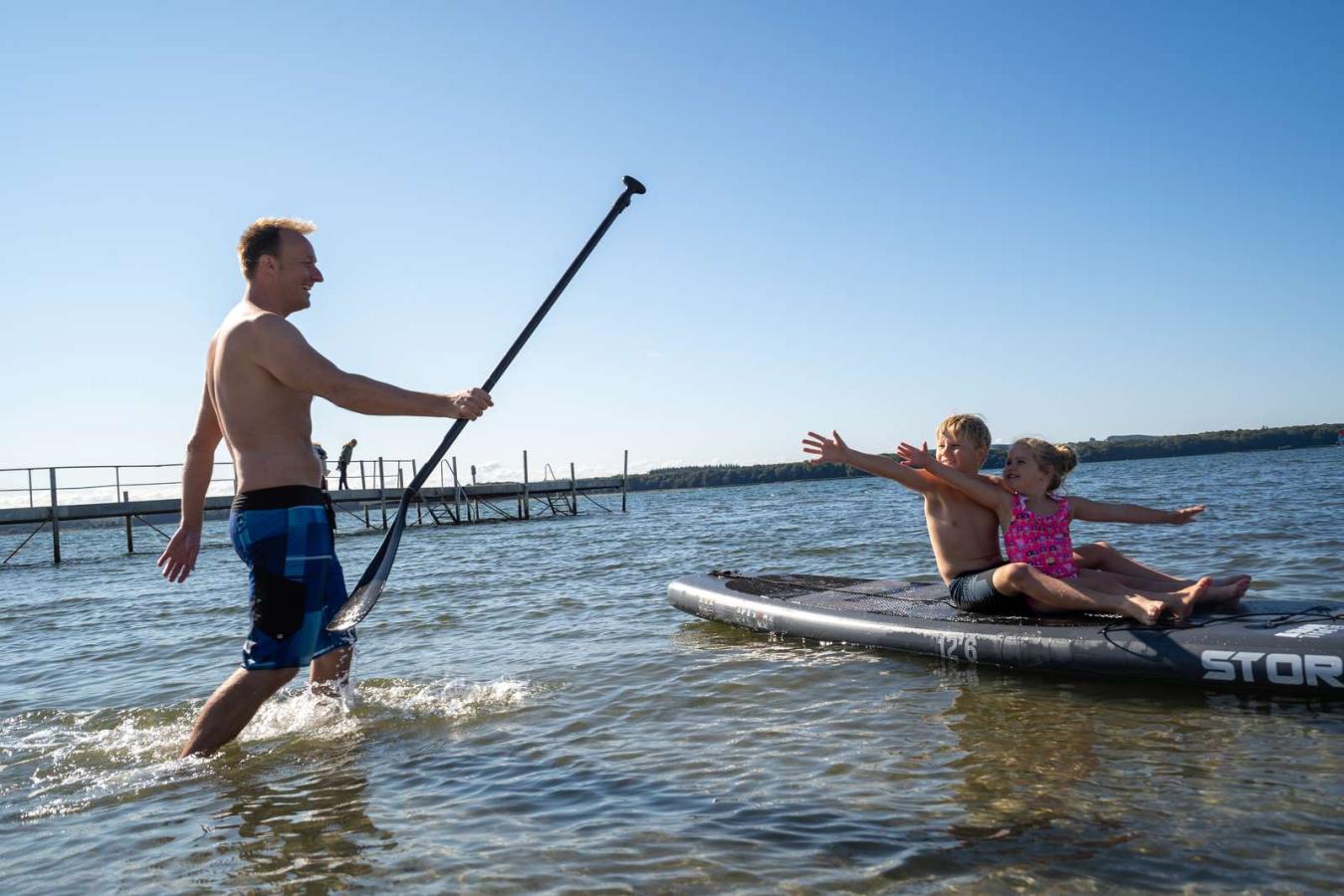 Kinder sitzen am Husodde Strand auf einem SUP-Board