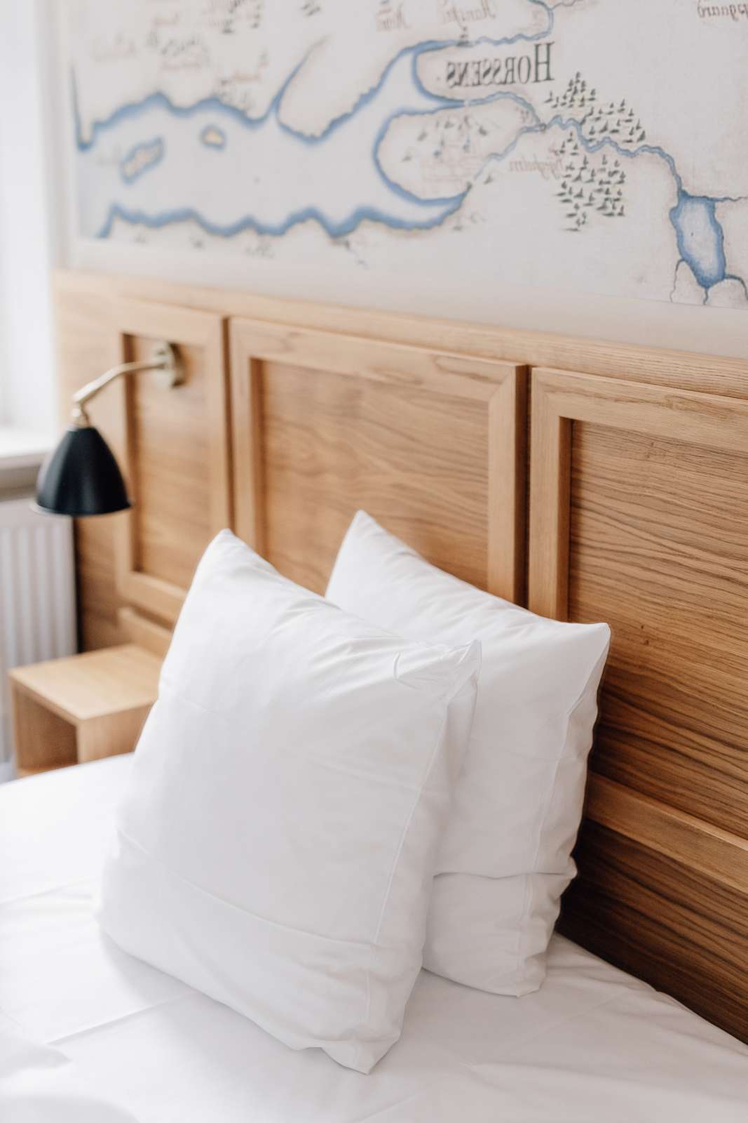 To puder står op af et hovedgærde af træ på en hotelseng 