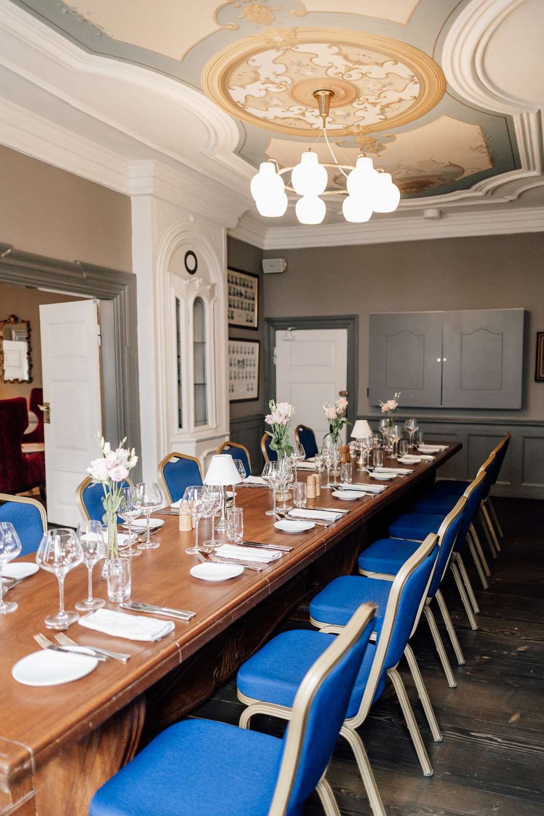 Mødelokale dækket med tallerkener og vinglas samt blå stole