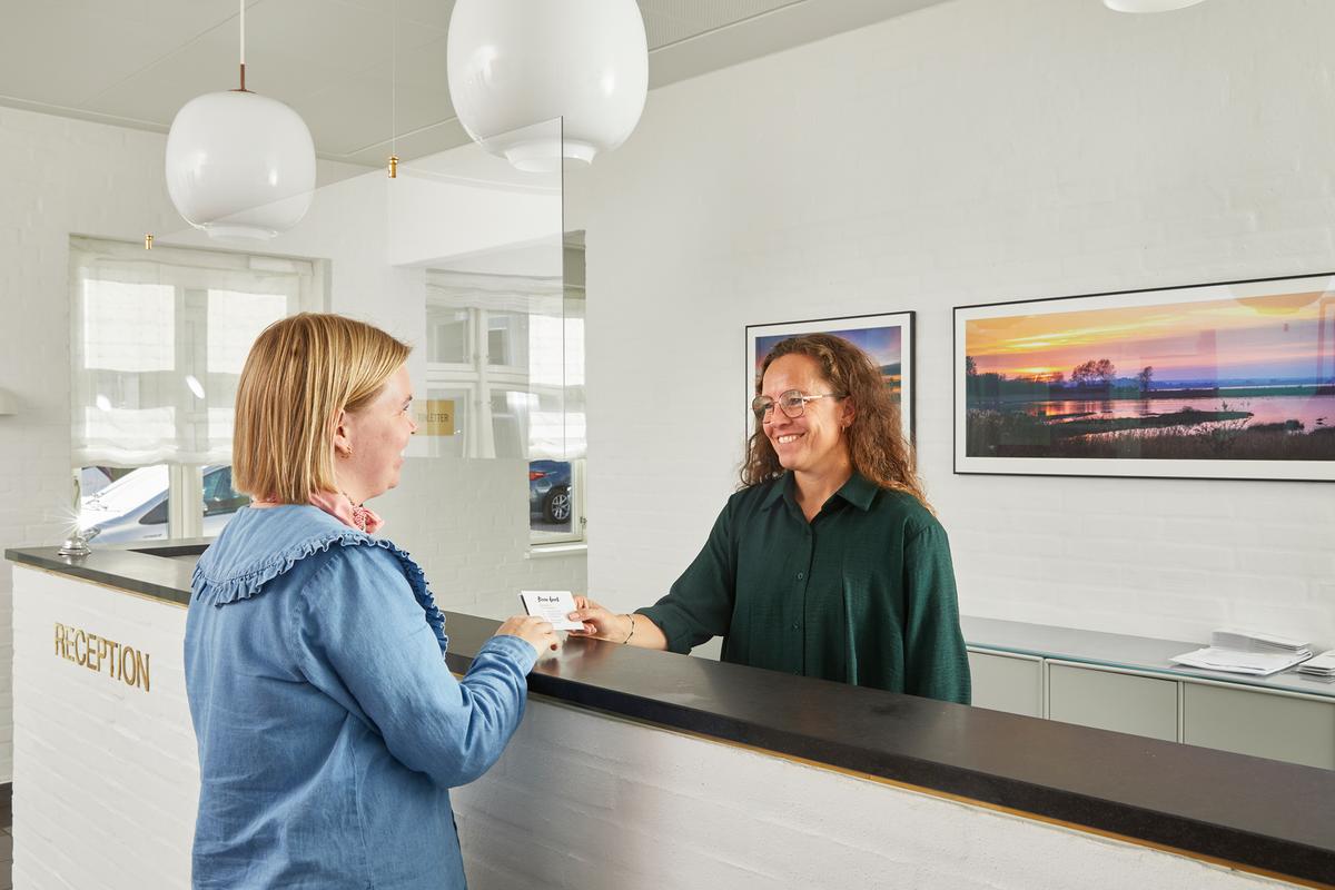 Receptionist giver visitkort til